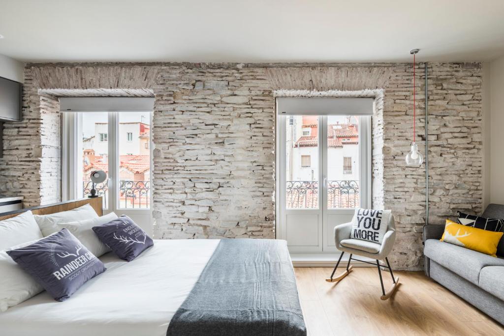 1 dormitorio con 1 cama grande y pared de ladrillo en APARTAMENTOS ELEVEN ROOMS, en Burgos