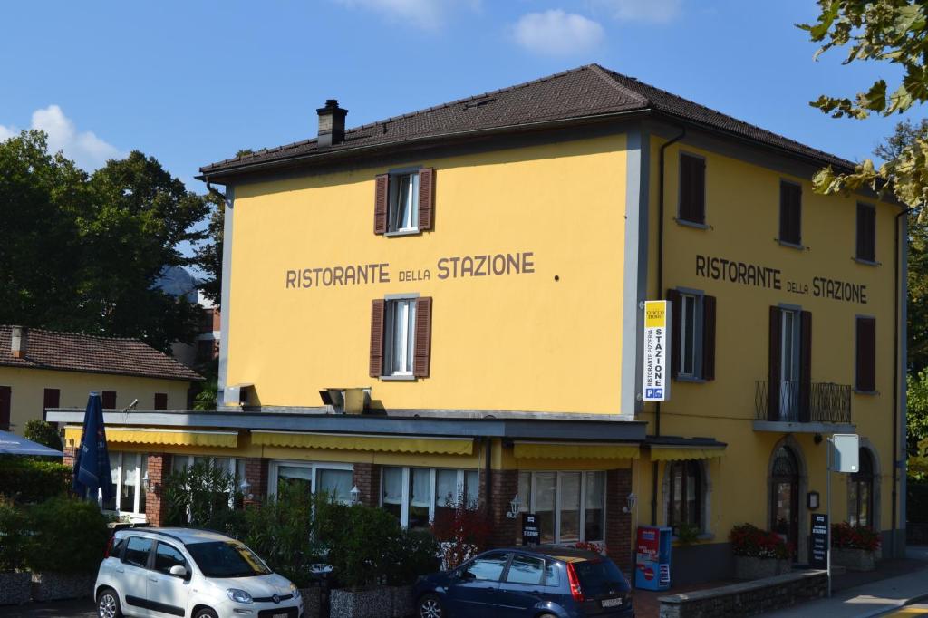 a yellow building with cars parked in front of it at Hotel della Stazione in Maroggia