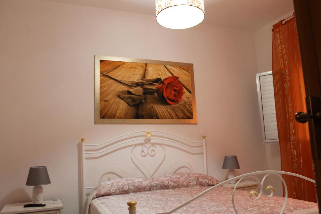ポルト・チェザーレオにあるSalento Roots Apartmentの白いベッドと壁に絵画が飾られたベッドルーム1室