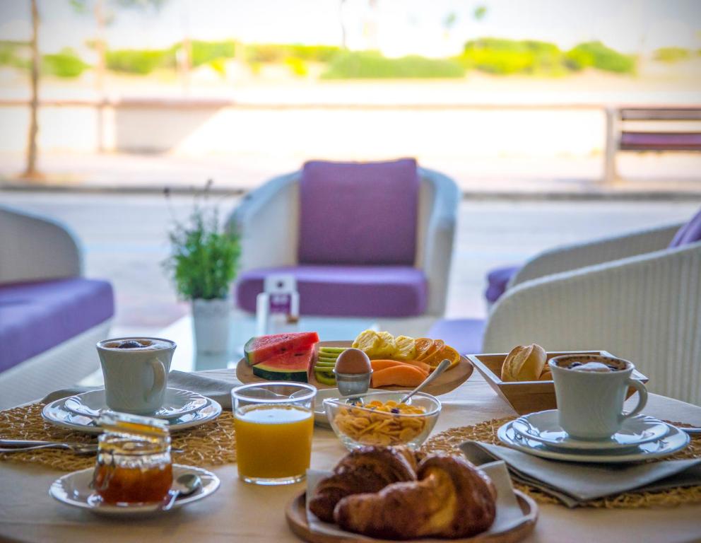 a table topped with plates of breakfast foods and drinks at Hotel Lux in Caorle
