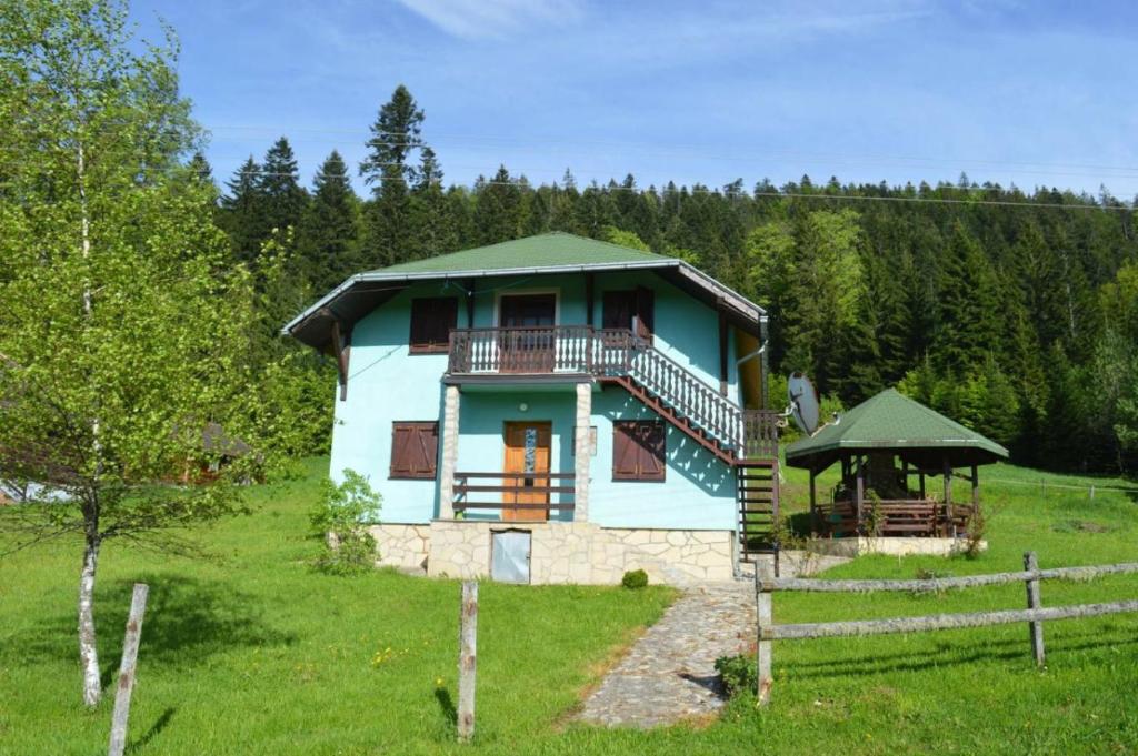 a blue house with a porch and a gazebo at Mystic Forest Hostel in Mitrovac