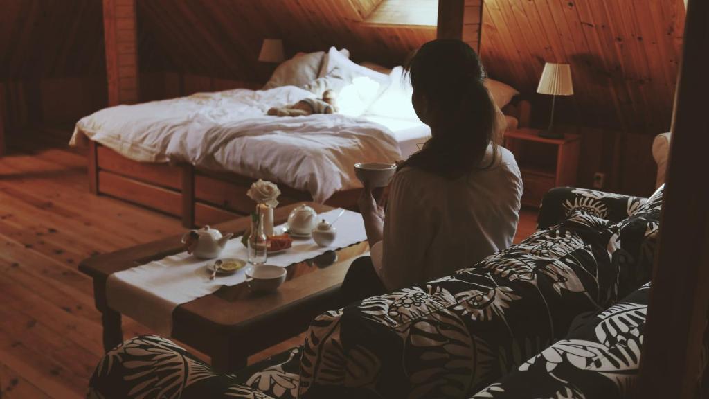 a woman sitting on a couch in a bedroom with a bed at Kamienica Sporting in Międzyzdroje