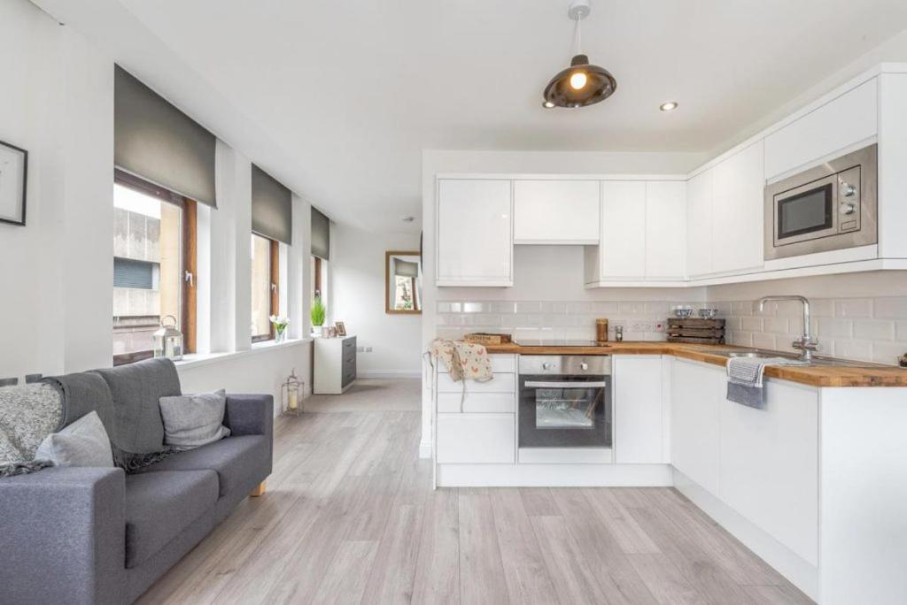 a kitchen and living room with white cabinets and a couch at Kirkgate Apartments in Bradford