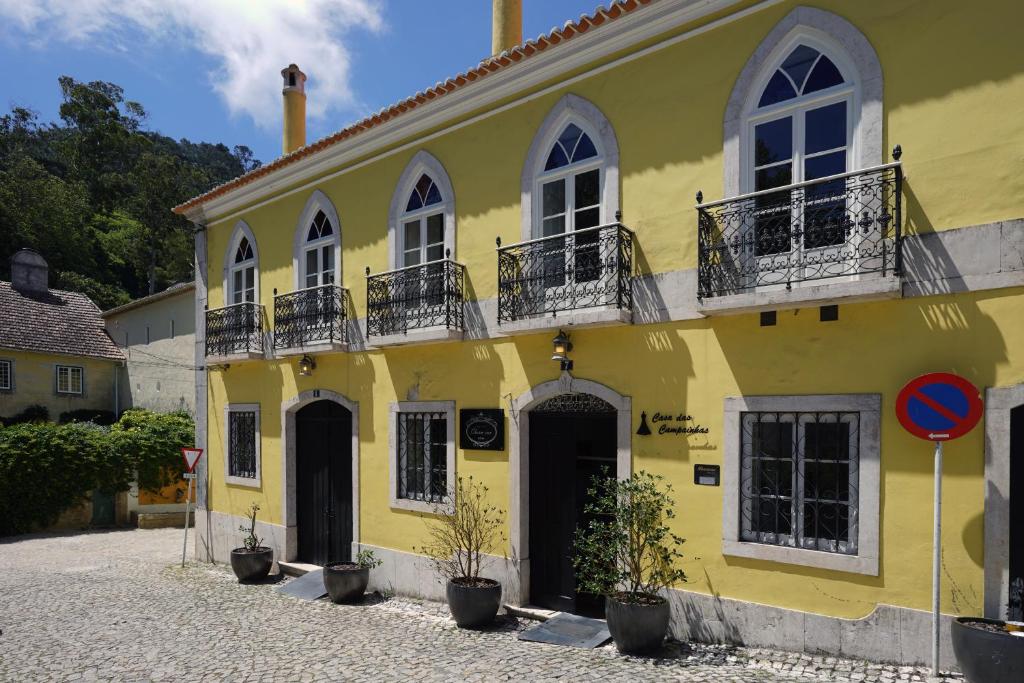 ein gelbes Gebäude mit Topfpflanzen davor in der Unterkunft Charm Inn Sintra in Sintra
