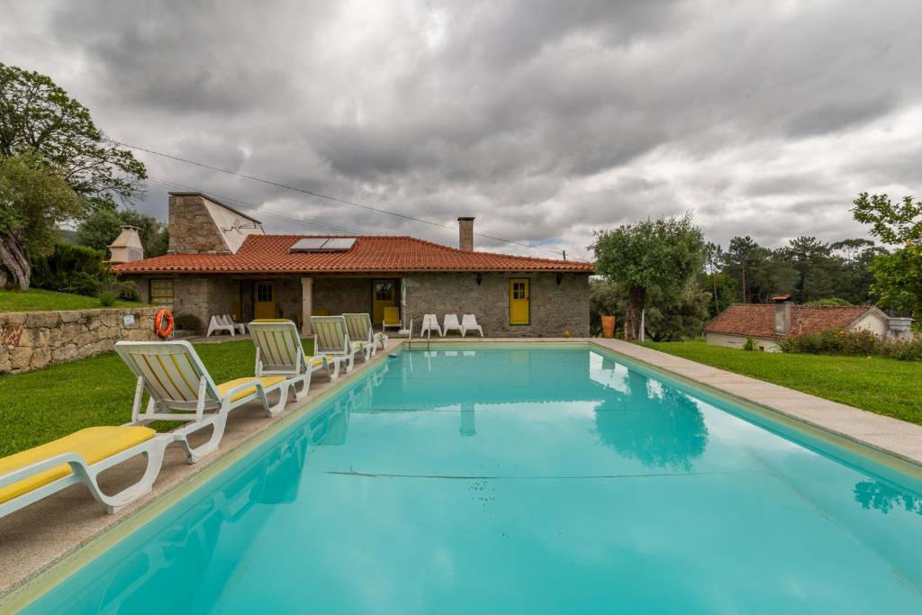 a swimming pool with chairs and a house at Eido Da Portela - Casa De Campo in Carregadouro