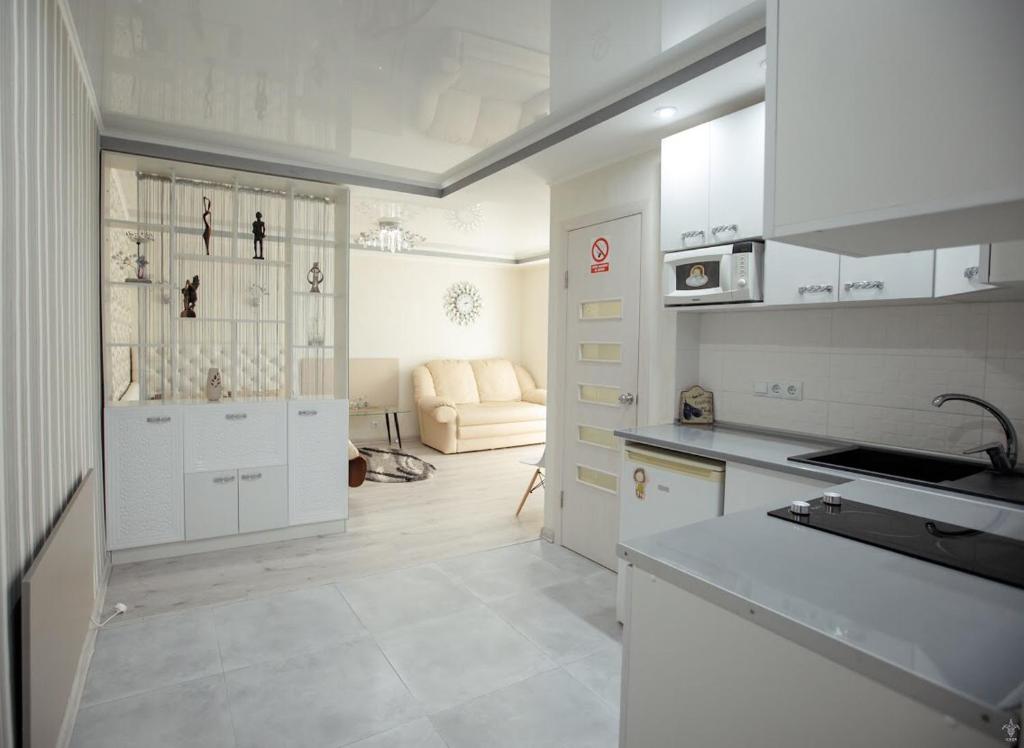 クロプィウヌィーツィクィイにあるApartments-studio on Gogolyaの白いキャビネットとソファ付きのキッチンが備わります。
