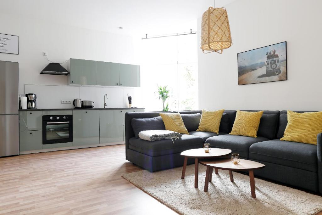 a living room with a blue couch and a kitchen at Be in Berlin Apartments in Prenzlauer Berg in Berlin