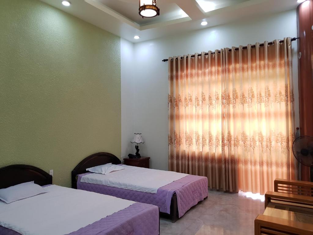a bedroom with two beds and a window at Khách sạn Anh Đào in Phủ Lý