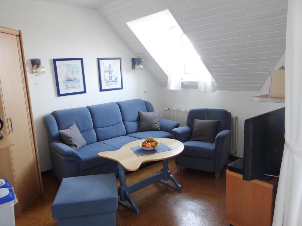 een woonkamer met een blauwe bank en een tafel bij 50097... in Carolinensiel