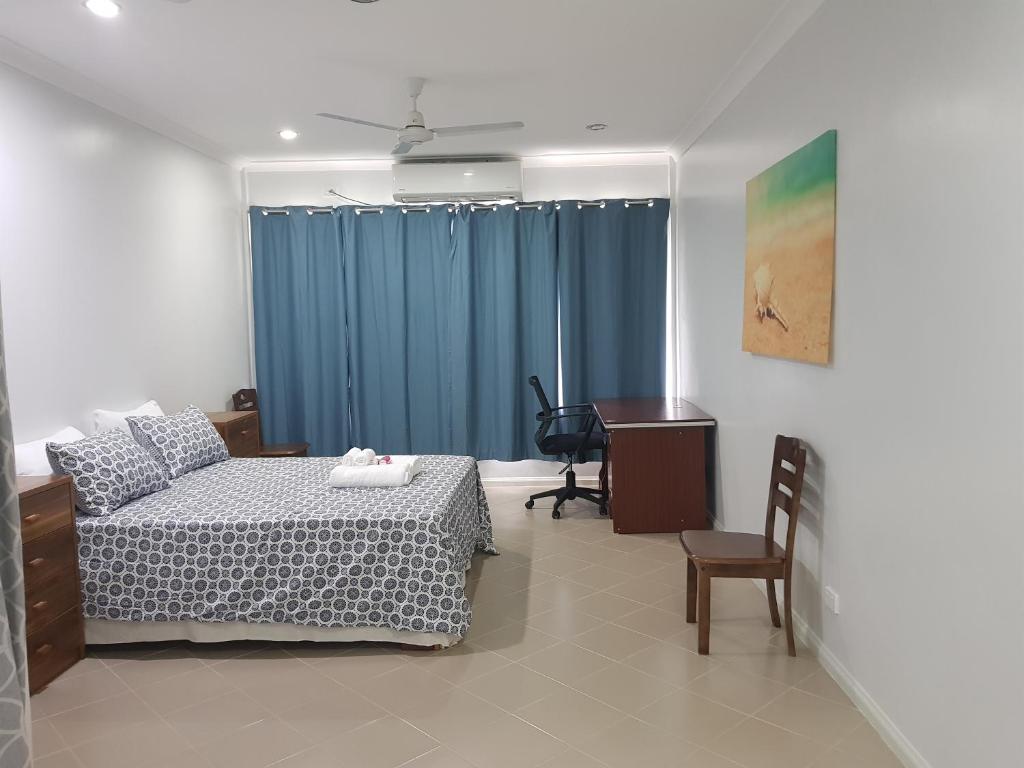 a bedroom with a bed and a desk and a table at Prestige Apartments - Solomon Islands in Honiara