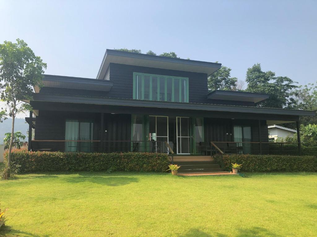 a black house with a lawn in front of it at Barn House Pong Ta Long in Pong Talong