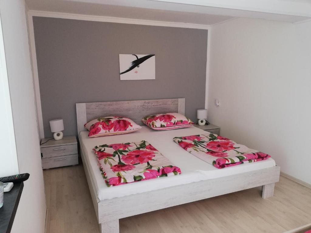 - une chambre avec un lit orné de fleurs roses dans l'établissement Ivana Apartment, à Rabac