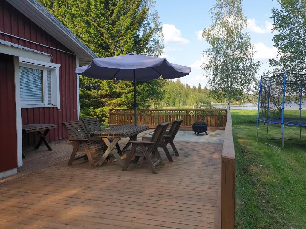 uma mesa e cadeiras de madeira com um guarda-sol num deque em Järvitalo em Soini