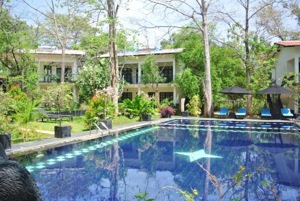 a swimming pool in front of a house at Flower Garden Eco Village in Sigiriya