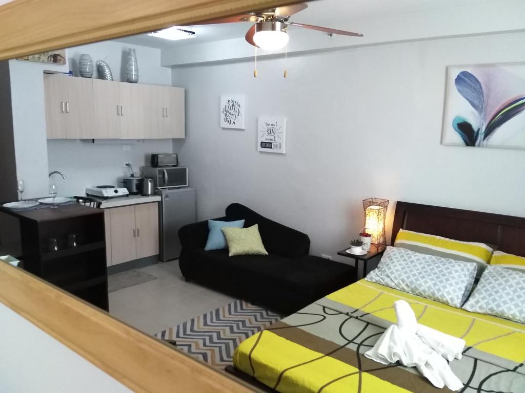 Mak'z Condo Place في ماكتان: غرفة معيشة مع سرير ومطبخ