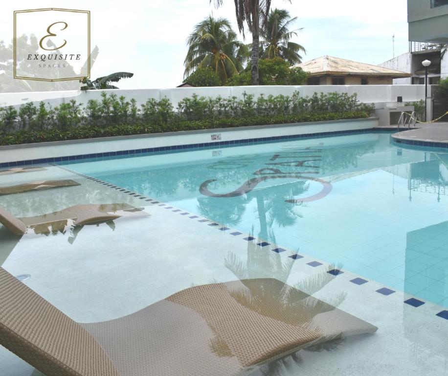 a swimming pool with two chairs and a building at Aimee Exquisite Spaces in Iloilo City