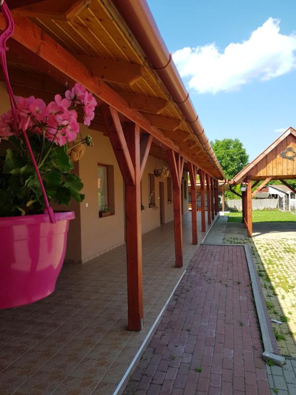 a covered walkway with pink flowers in a pot at Tisza-Tavirózsa Vendégház in Tiszaszőlős