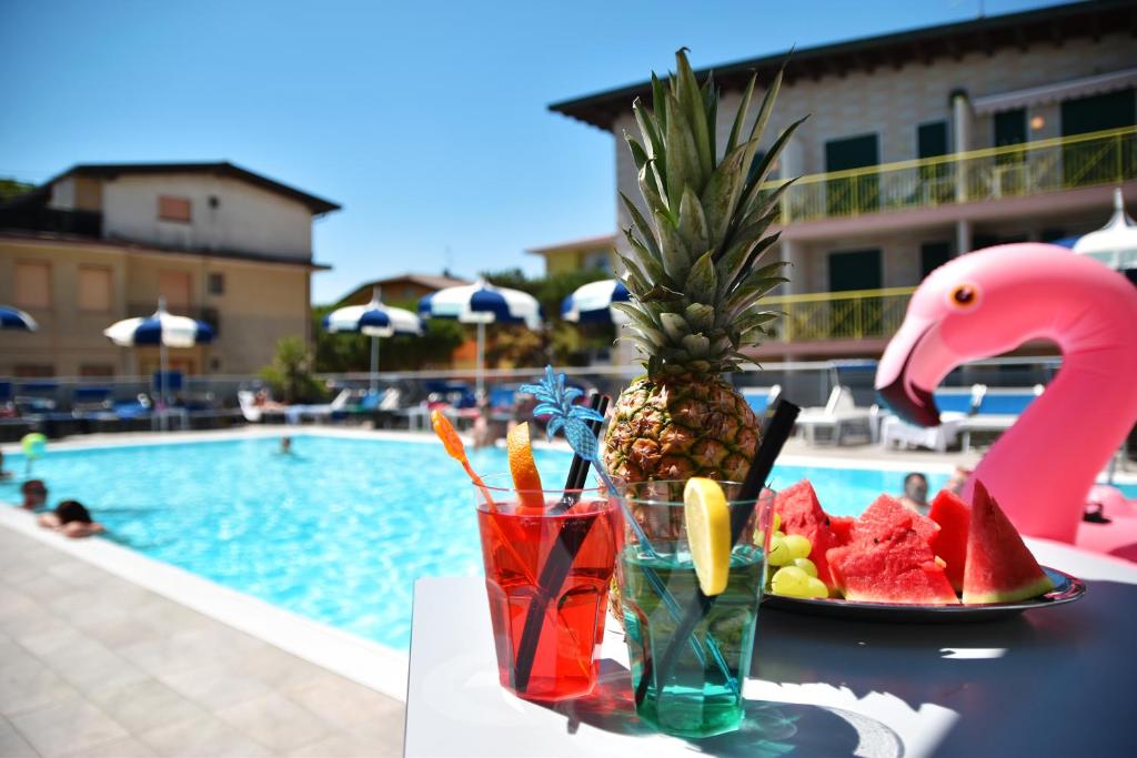 a table with a pineapple and a plate of fruit next to a pool at Hotel Bristol in Caorle