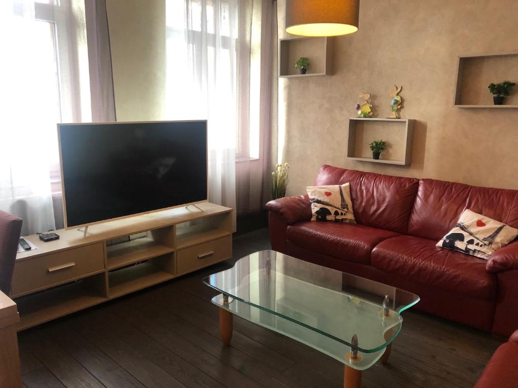 sala de estar con sofá rojo y TV de pantalla plana en Residence du Galtz en Colmar