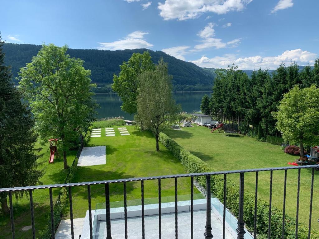 a balcony with a view of a park and a lake at Villa Stiegl in Steindorf am Ossiacher See