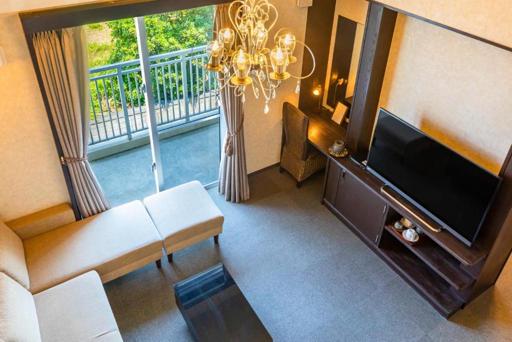 a living room with a flat screen tv and a chandelier at Kerama Terrace in Tokashiki