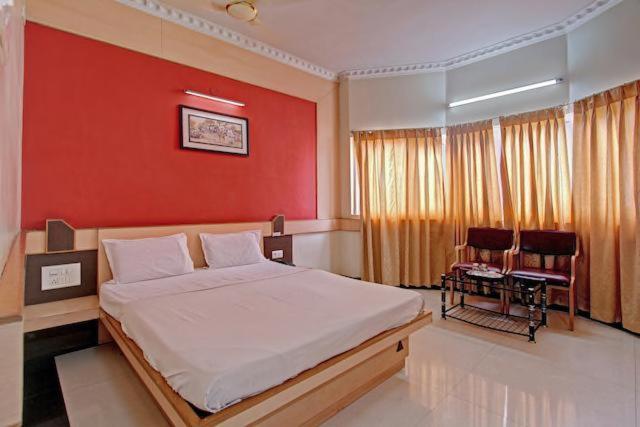 um quarto com uma cama grande e uma parede vermelha em Bharati Lodge em Hubli