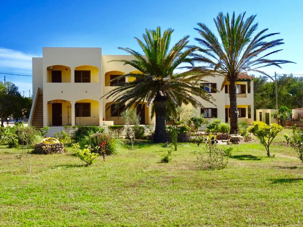 una casa con dos palmeras delante de ella en Apartamentos Verde Mar, en Es Pujols