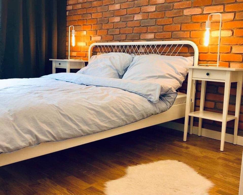 a bedroom with a bed and a brick wall at Lofty & Apartamenty Garnizon Gdańsk in Gdańsk