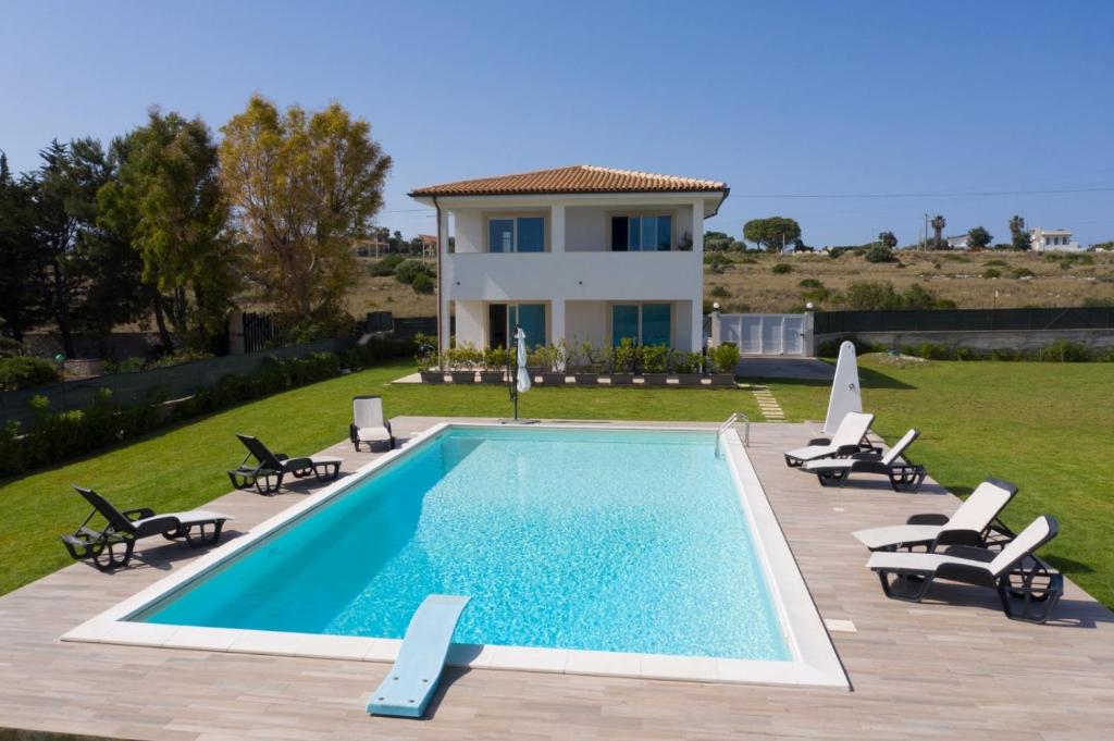 a villa with a swimming pool in front of a house at Villa Zaffiro in Siracusa