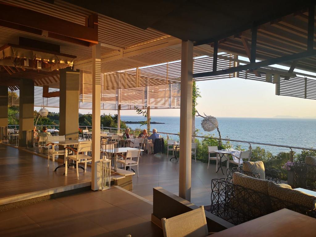 a restaurant with tables and chairs and a view of the ocean at Mare Dei Suites Hotel Ionian Resort in Skafidia