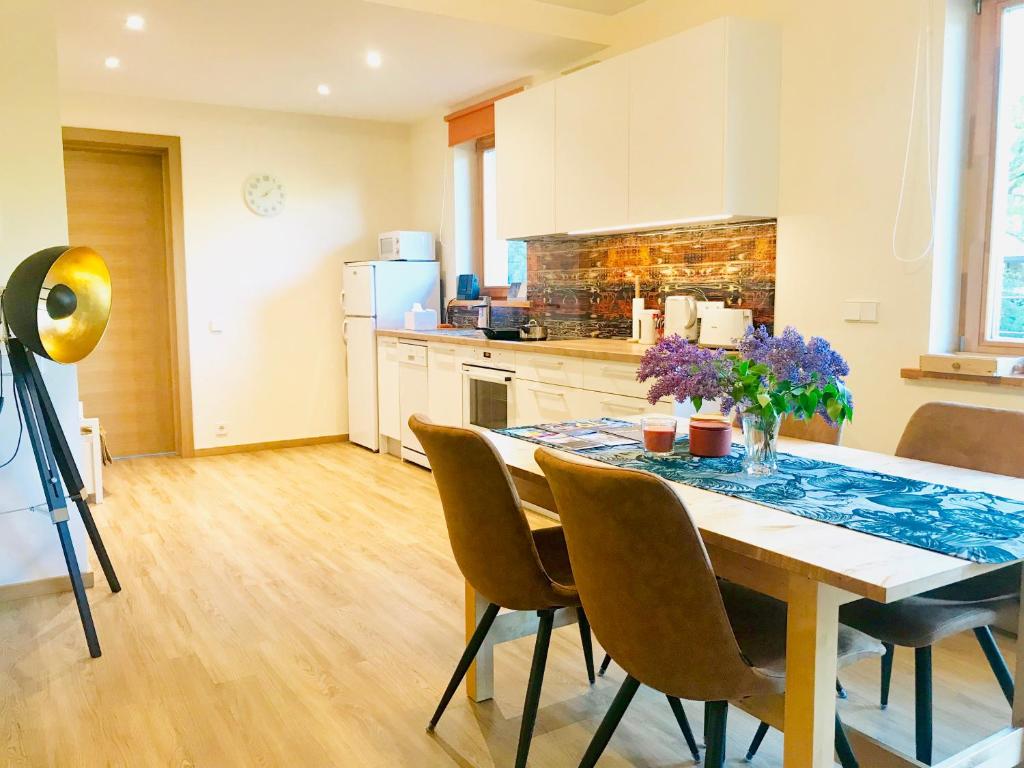 a kitchen with a dining room table with chairs and flowers at Family apartment 100m from the beach in Jūrmala