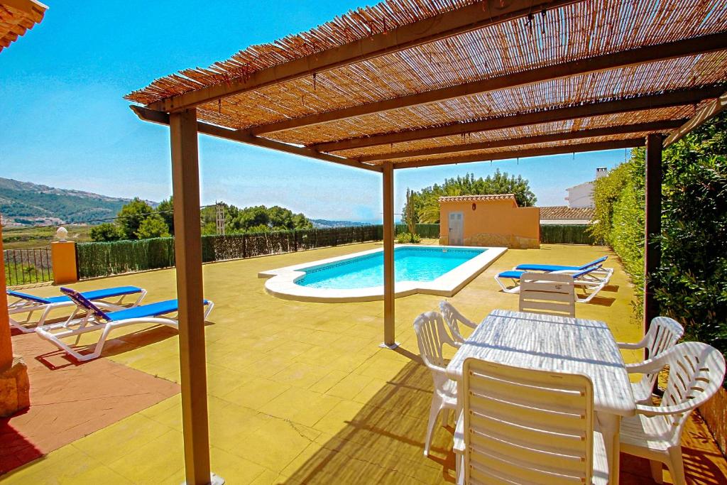 un patio con mesa y sillas y una piscina en Marques - holiday home with private swimming pool in Benitachell, en Benitachell