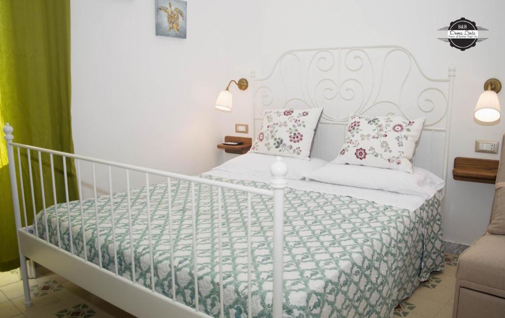 um quarto com uma cama branca e almofadas cor-de-rosa em Domus Linda B&B em Ischia