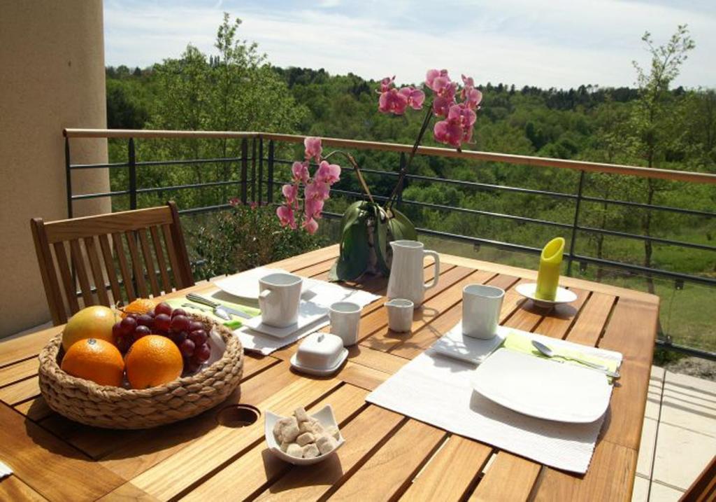 une table en bois avec une corbeille de fruits sur un balcon dans l'établissement Chambre d'hôtes La Dentalie, à Rouffignac-Saint-Cernin-de-Reilhac
