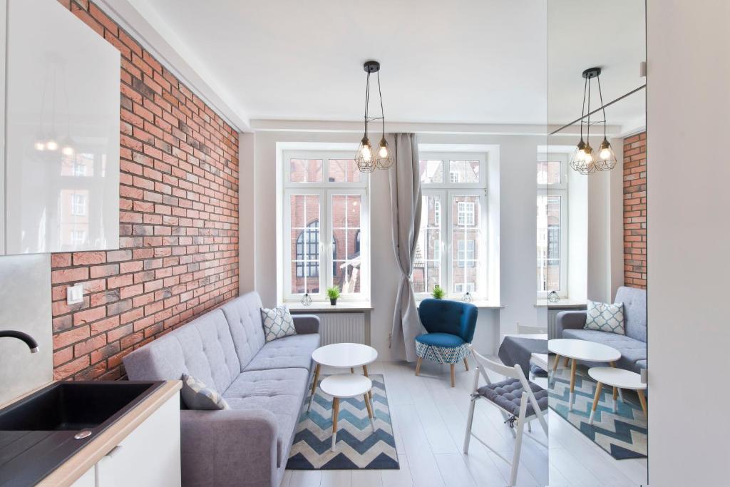 a living room with a couch and a brick wall at YOURAPART Chlebnicka Centrum in Gdańsk