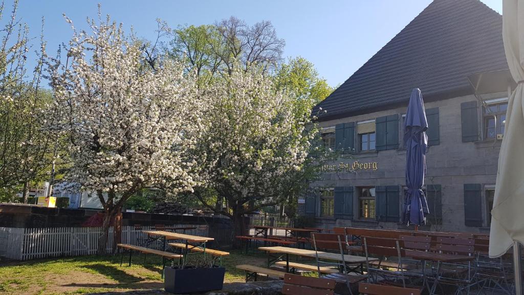 Un bâtiment avec un tas de tables de pique-nique et d'arbres dans l'établissement Hotel und Gasthof Ritter St. Georg, à Erlangen