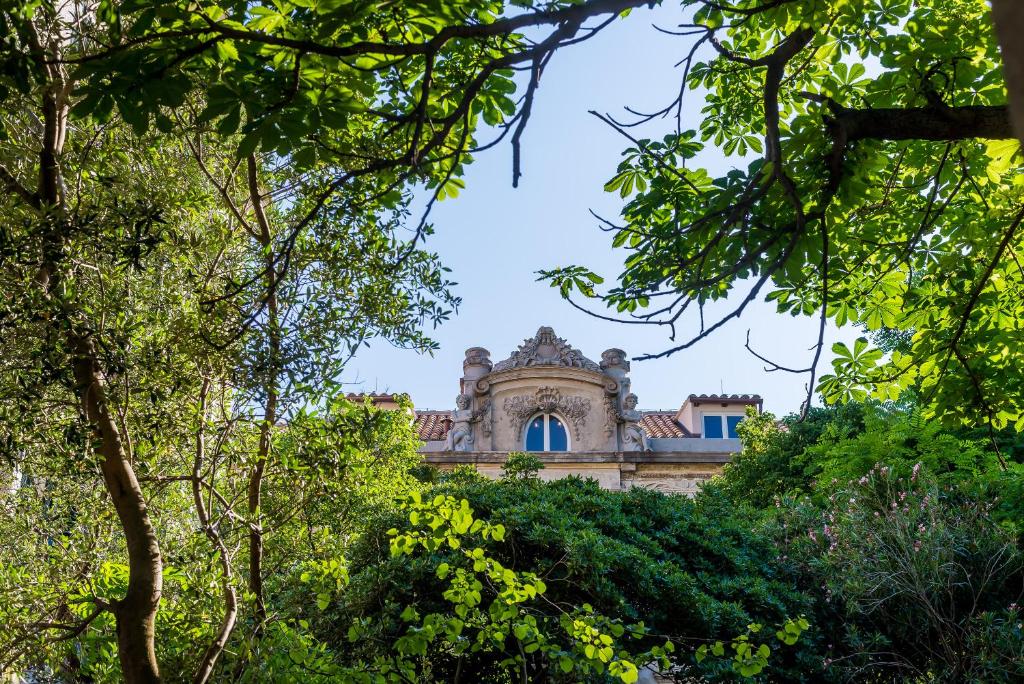 an old building through the trees at Villa Roma in Dubrovnik