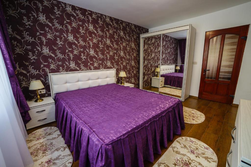 a bedroom with a purple bed and a mirror at ROMANTIK APARTMENTS in Câmpulung Moldovenesc