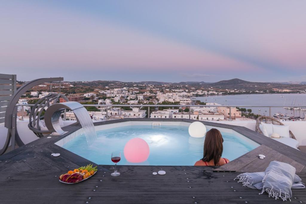 a woman sitting on a table next to a swimming pool at Uncle's House luxury Suites in Adamas