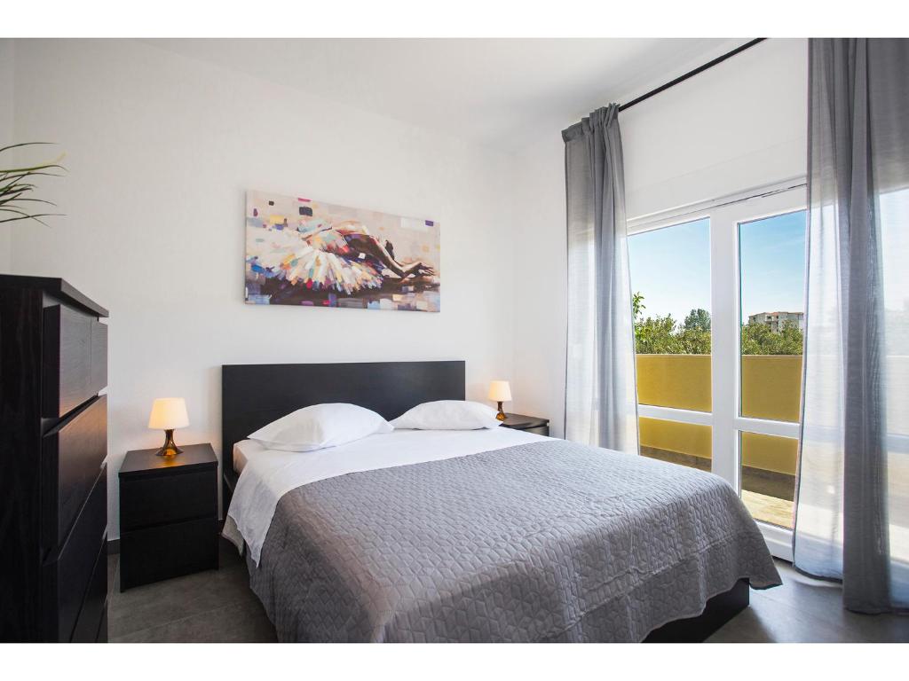een slaapkamer met een bed en een groot raam bij Olive Tree Apartments in Split