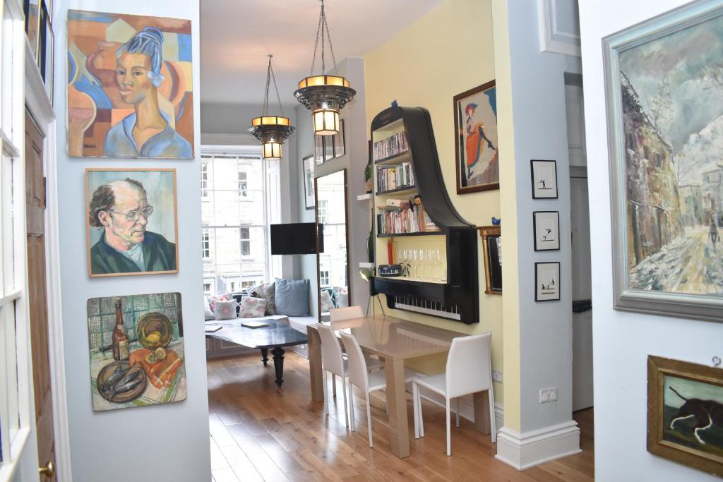 a dining room with a table and paintings on the walls at Frederick Street - stylish apartment in the heart of New Town! in Edinburgh