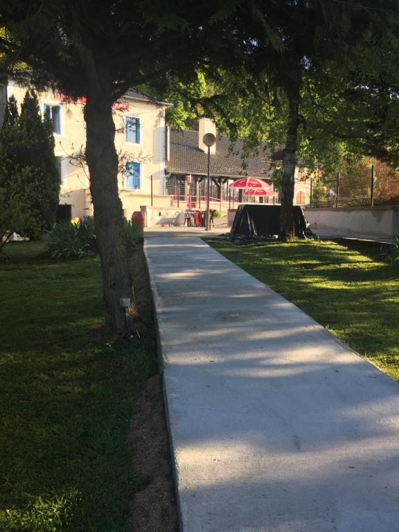 a sidewalk in a park with trees and a building at La Table Des Bons Peres in Bislée