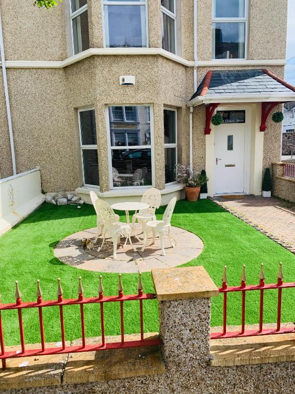 two chairs and a table in the yard of a house at The Snug Garden Apartment in Llandudno