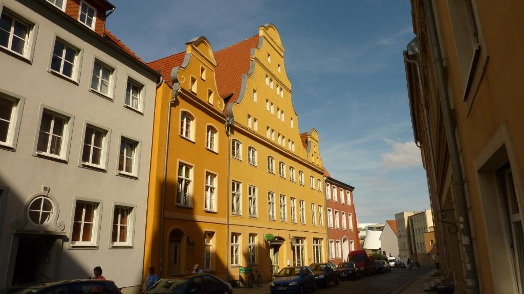 eine Reihe von Gebäuden mit Autos, die auf einer Straße geparkt sind in der Unterkunft Altstadt Pension Hafenblick in Stralsund