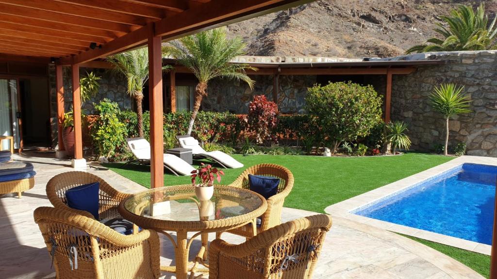 un patio con mesa, sillas y piscina en Villa Luxe Tauro Mogan, en Puerto Rico de Gran Canaria