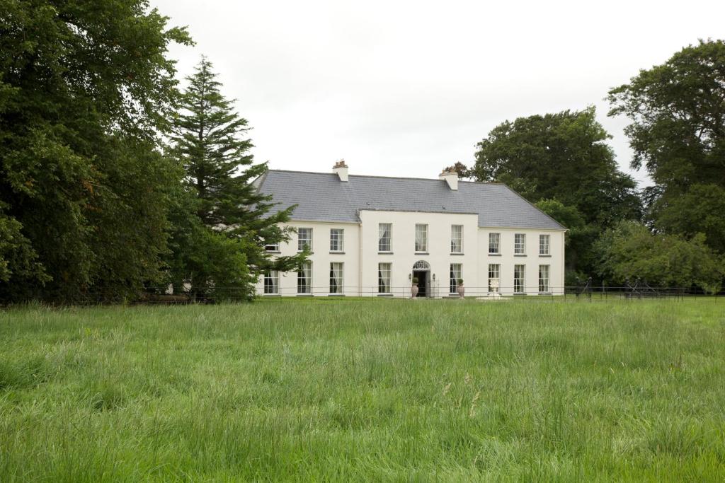 uma grande casa branca com um grande campo de relva em Grange Manor em Ballyragget