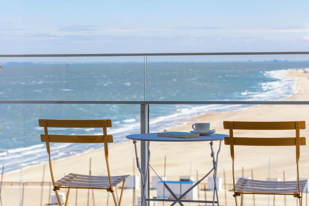 two chairs and a table on a balcony with the beach at knokkeappart Studio 2 pers in Knokke-Heist