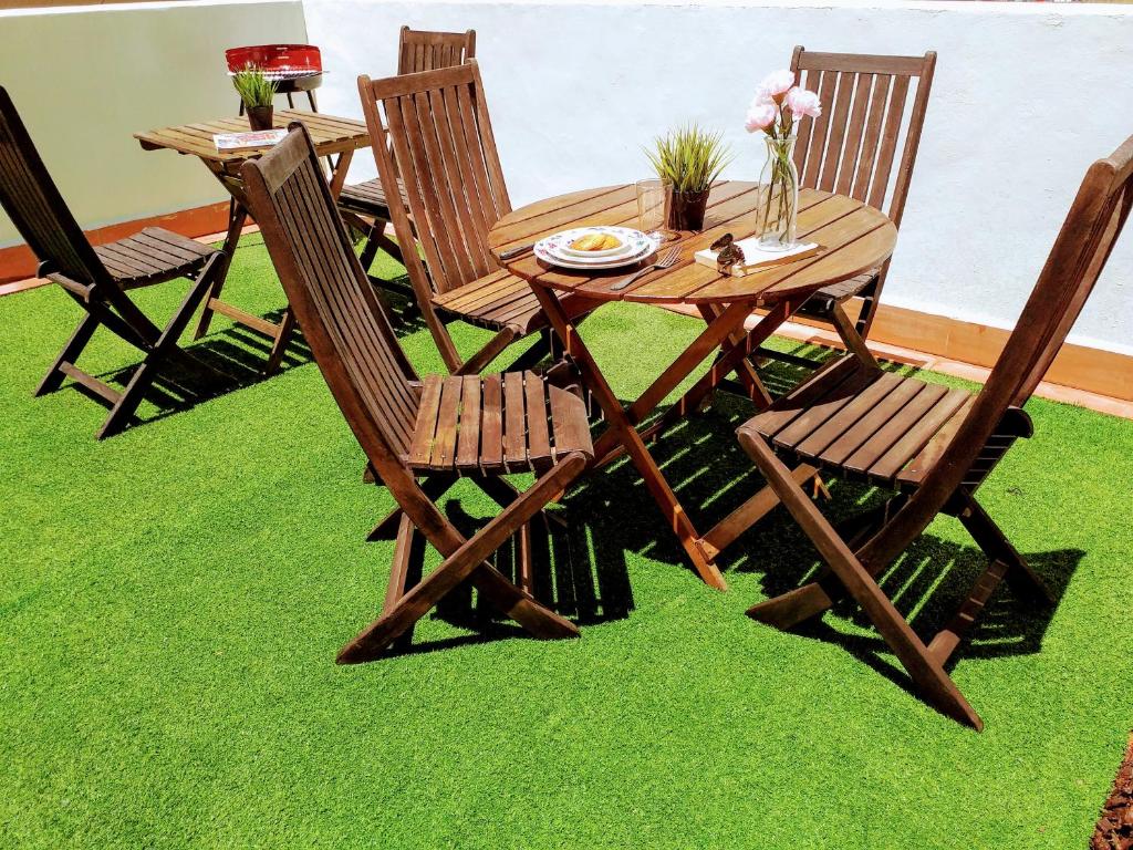 a wooden table and chairs on green grass at LARGE Apartment with large and sunny Terrace - Garden & Outdoor Gym , ALICANTE CENTER in Alicante