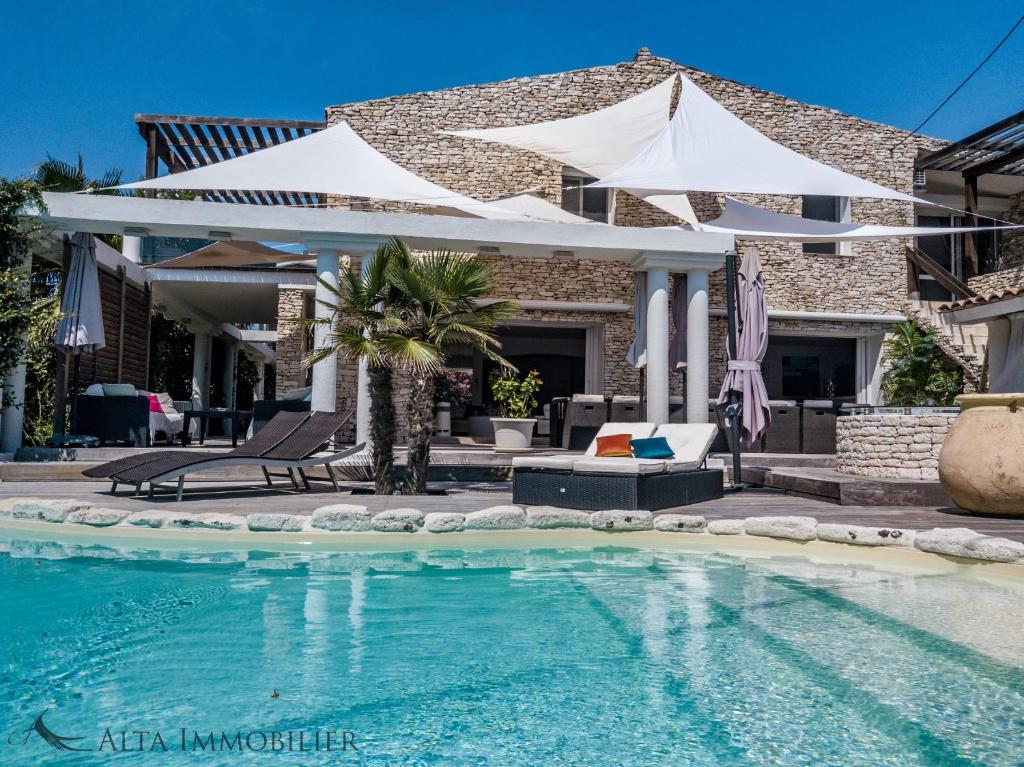 a swimming pool with two white umbrellas and a house at Petra-Bianca in Bonifacio