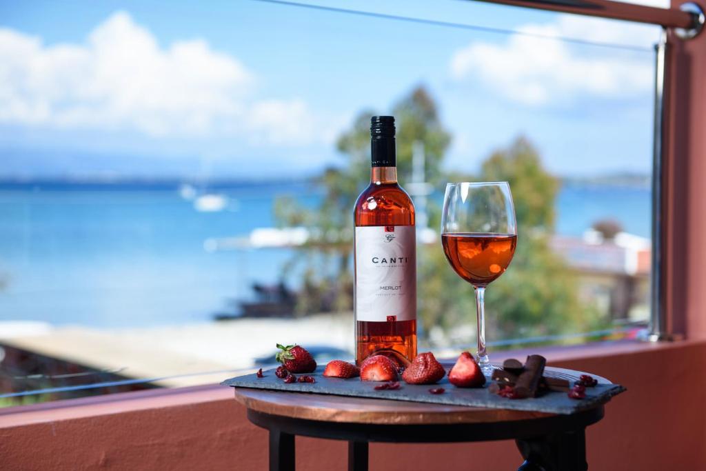 a bottle of wine and a glass on a table with strawberries at Corfu Seaview Maisonette - Sopra il Mare in Petrití